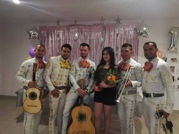 Serenata de cumpleaños con mariachi juvenil: la cumpleañera con un ramo de flores frente a una decoración de globos y estrellas